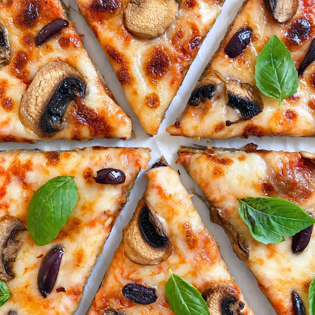 sliced 2-ingredient pizza crust finished pizza with fresh basil leaves