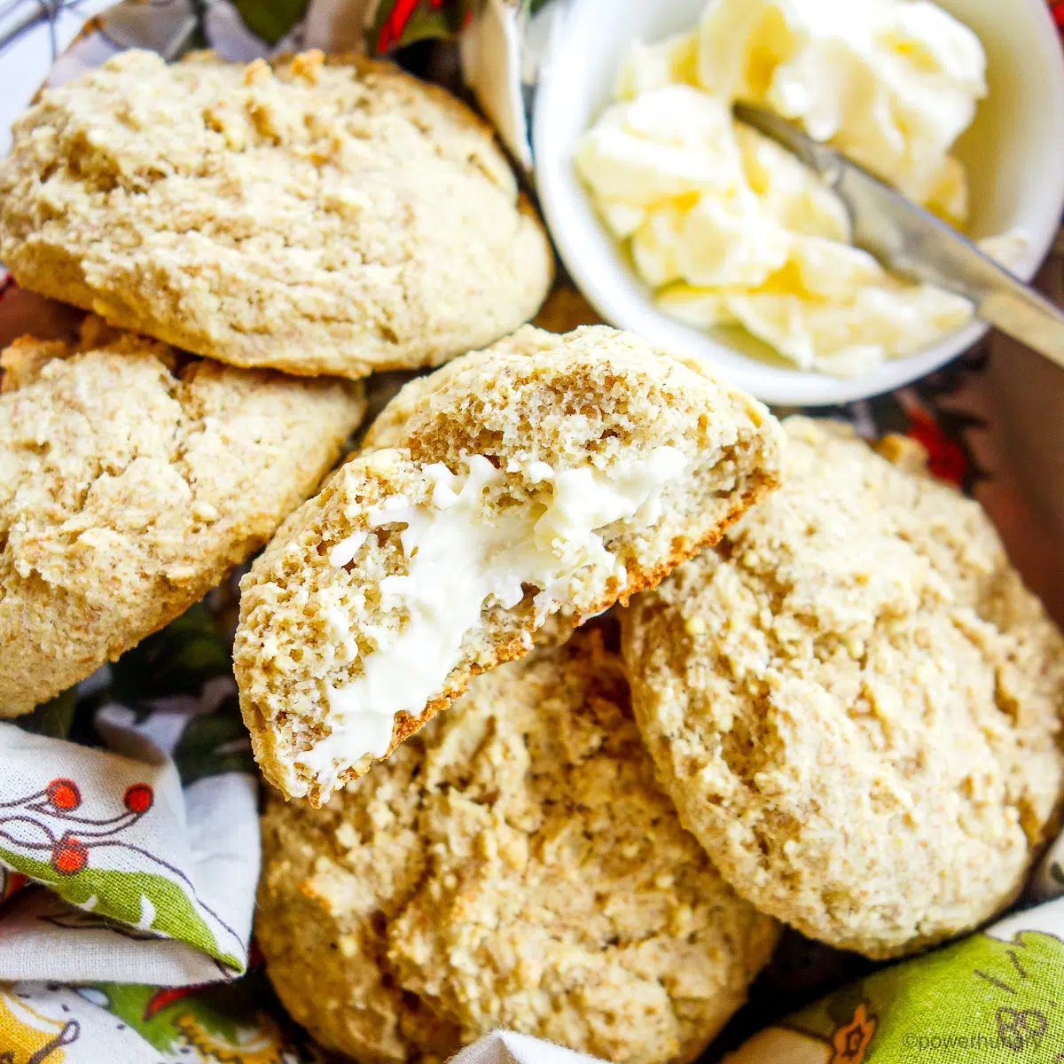 basket of millet biscuits with one spread with vegan butter