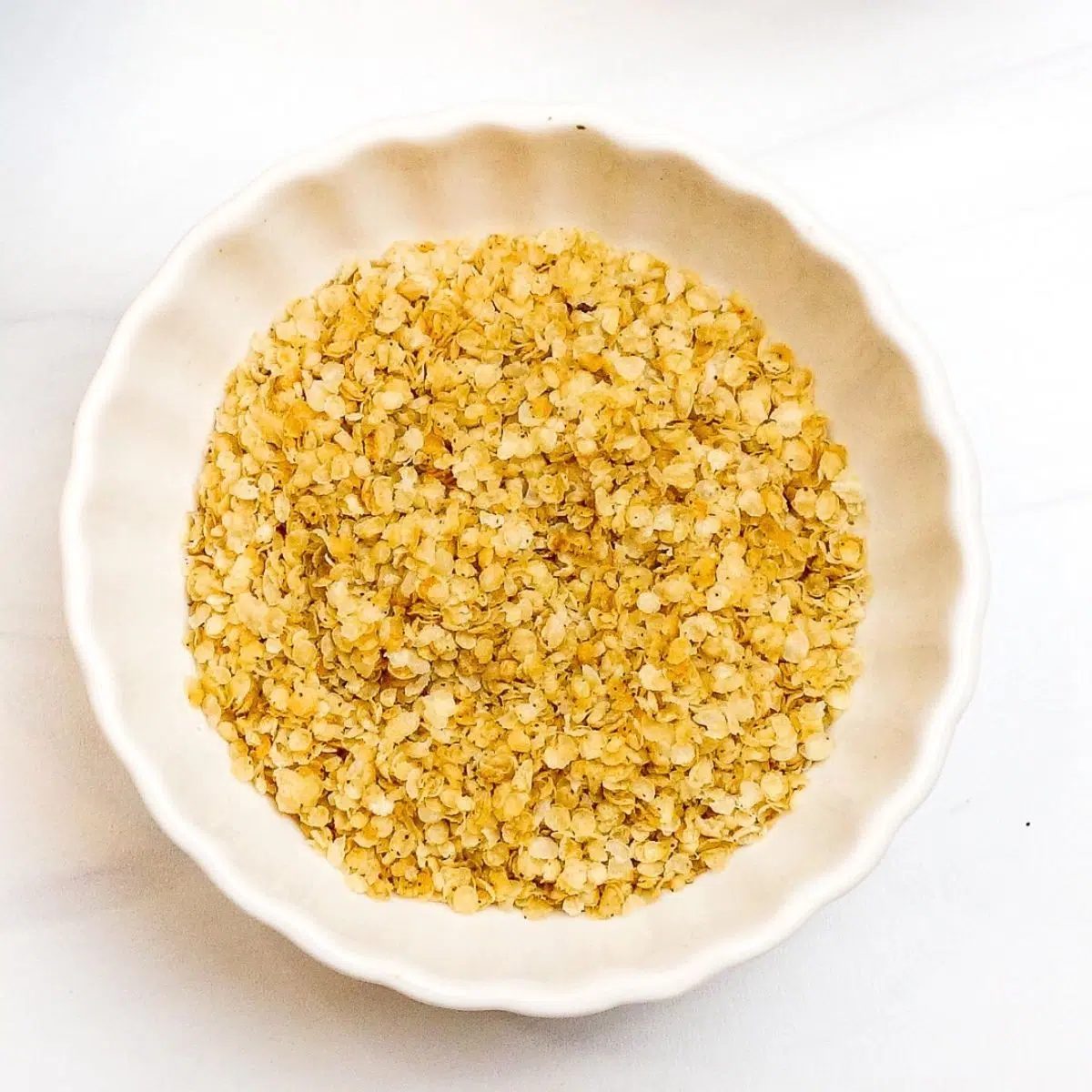 white scalloped bowl filled with millet flakes