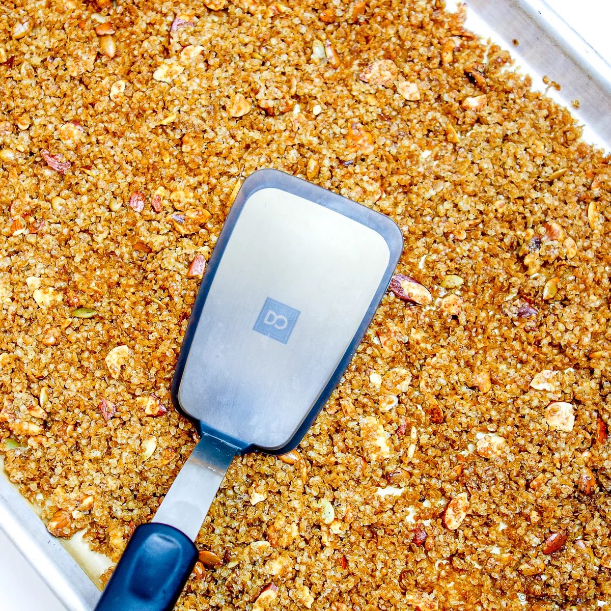 baked millet granola getting tamped with a spatula