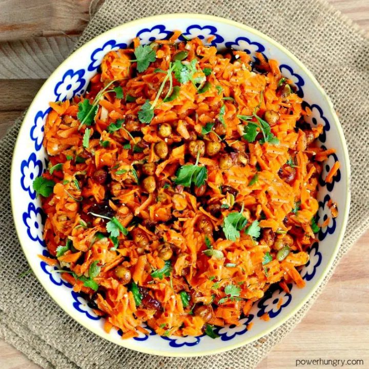 Moroccan Carrot Chickpea Salad in a blue and white bowl sitting atop a piece of burlap
