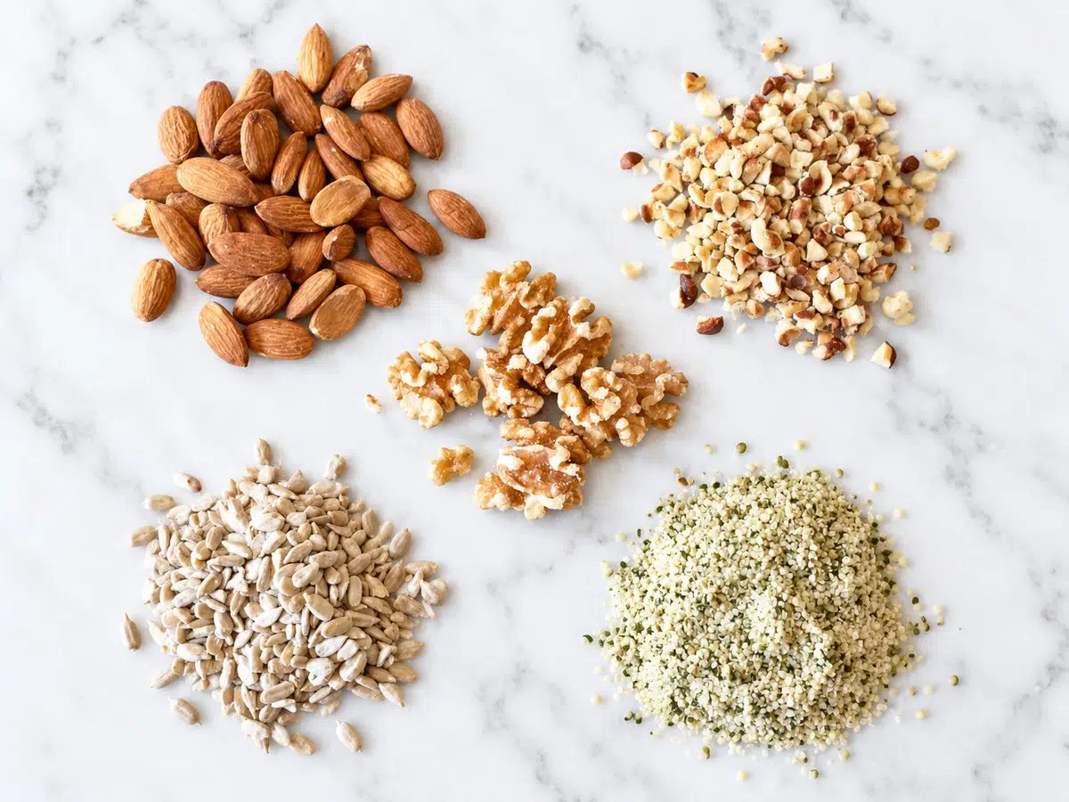 assorted nuts and seeds on a white marble surface