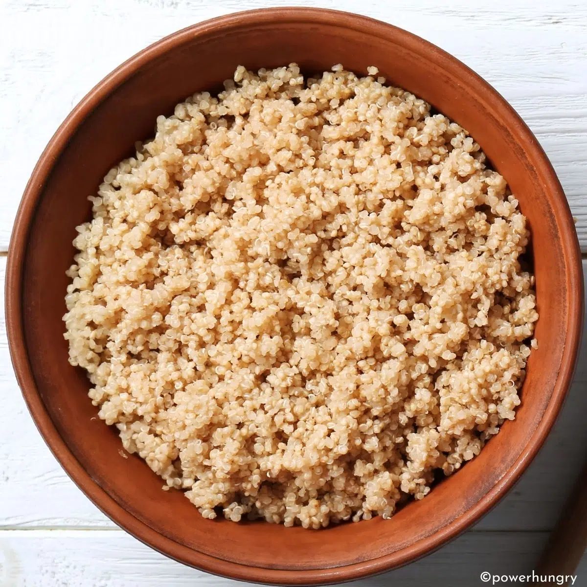 wooden bowl filled with cooked quinoa on a white board background