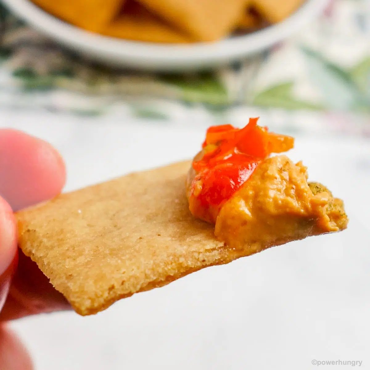 close up of a cassava cracker with hummus on one end