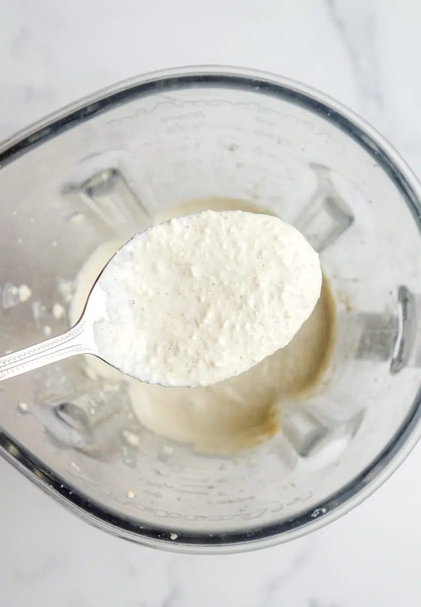 closeup of a spoonful oft cracker batter above a blender full of batter