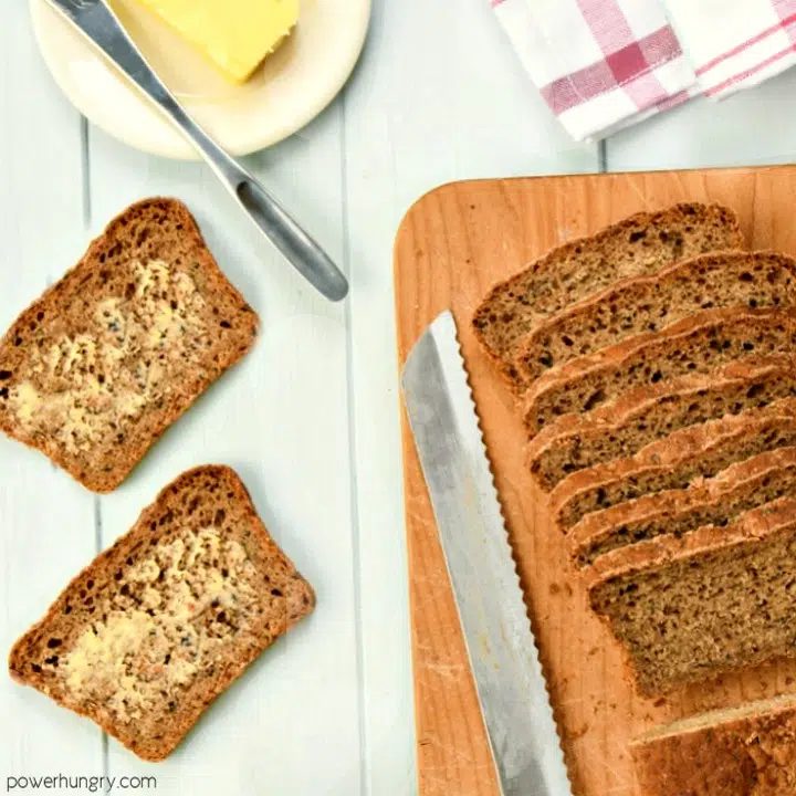 mini loaf of walnut oat blender bread, sliced, on a wooden cutting board