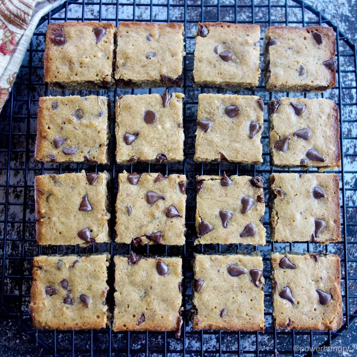 vegan banana blondies on a black cooling rack, cut into 16 pieces