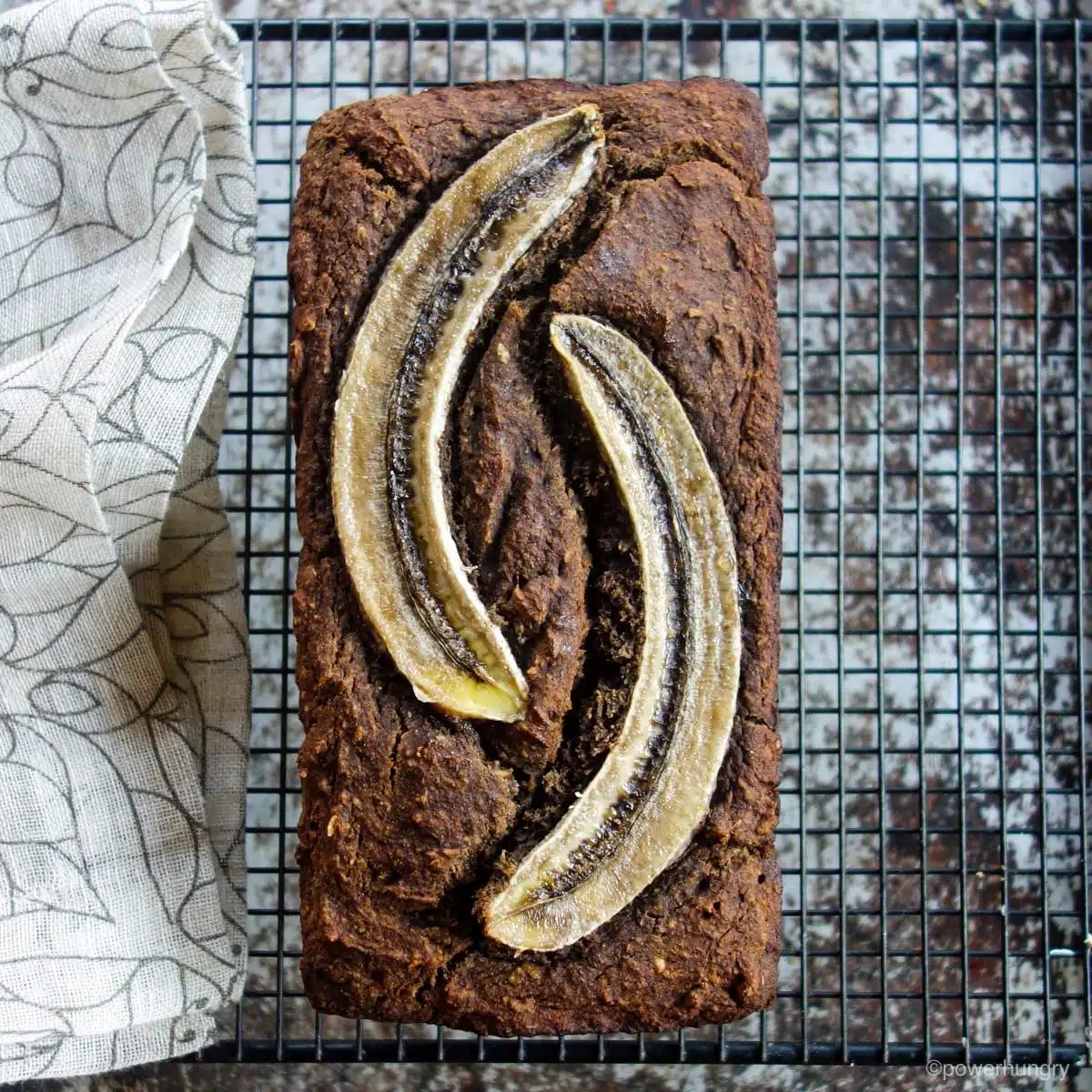 loaf of bread, topped with slice bananas, on a cooling rack