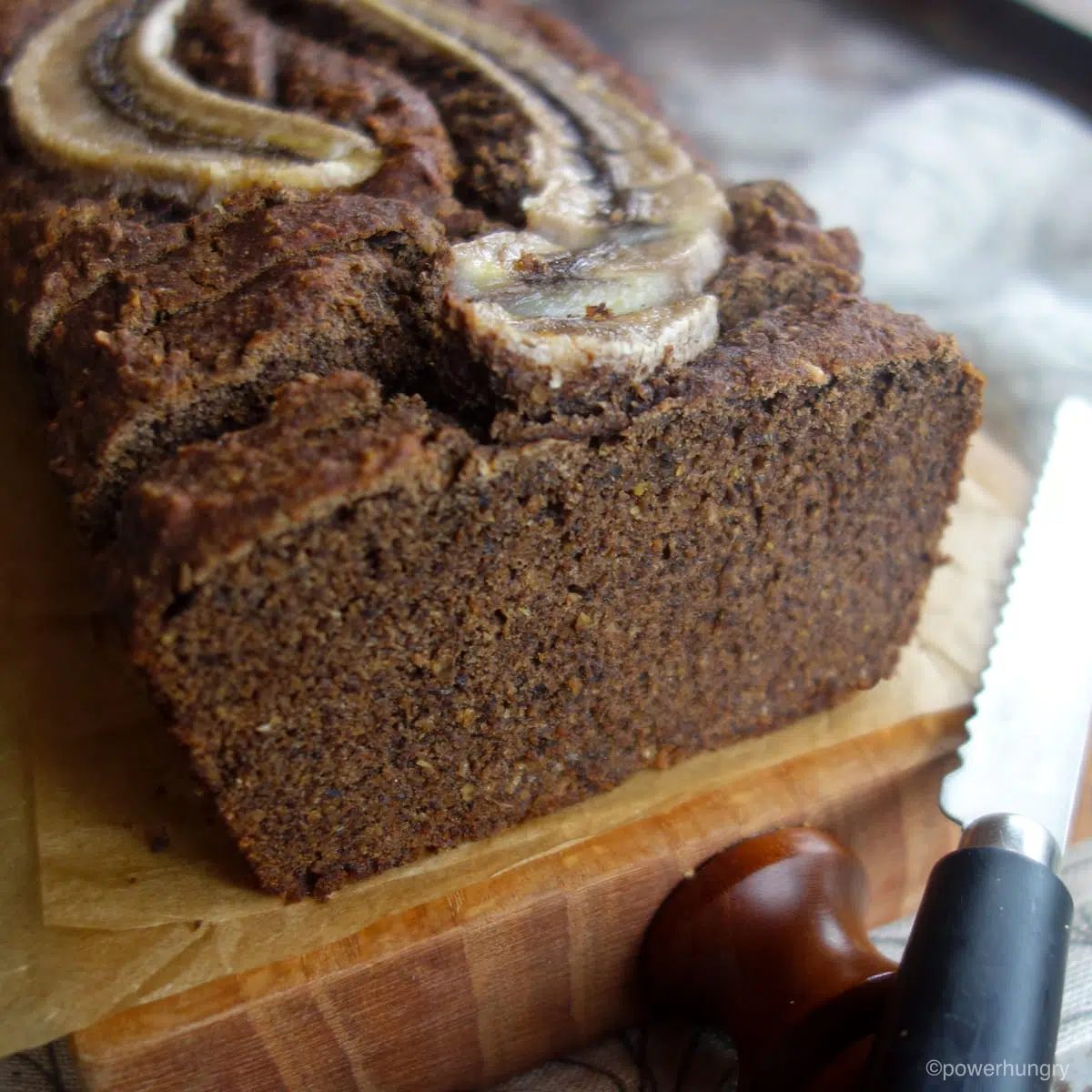 close up of one cut end of a loaf of banana bread, on a wood cutting board