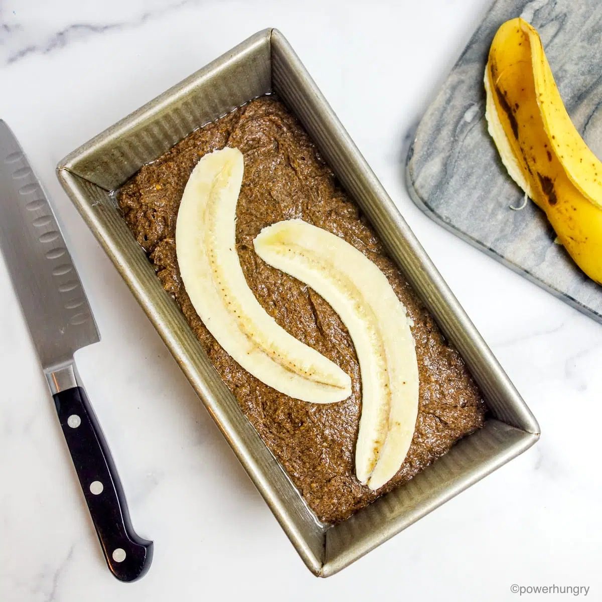 unbaked loaf of buckwheat banana bread with sliced bananas on top