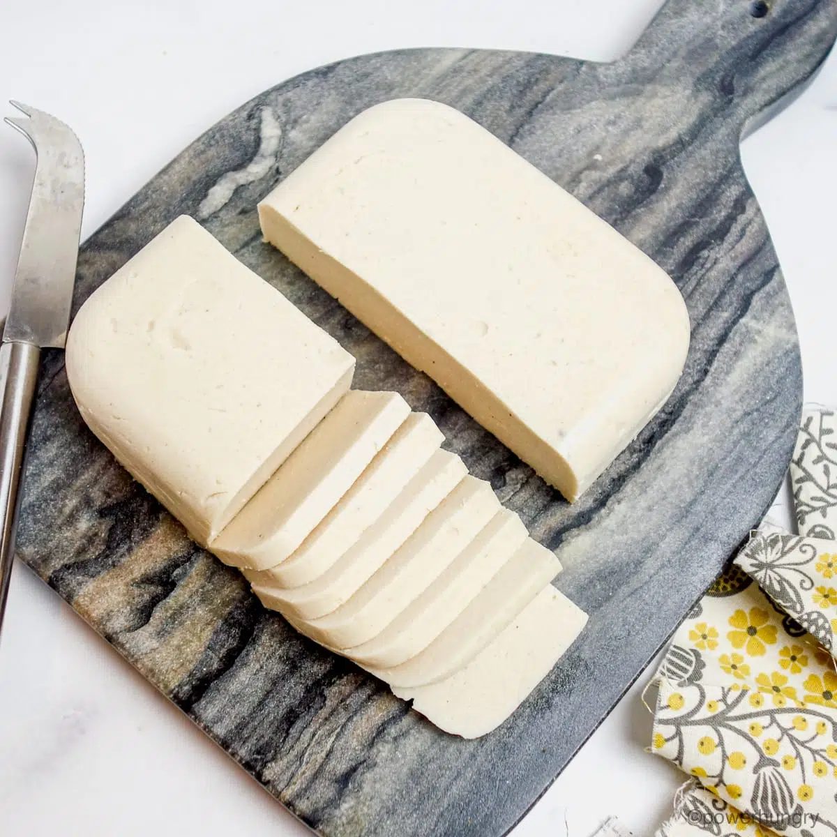 sliced Oil-Free Vegan Mozzarella that Melts, Grates & Slices on a cutting board