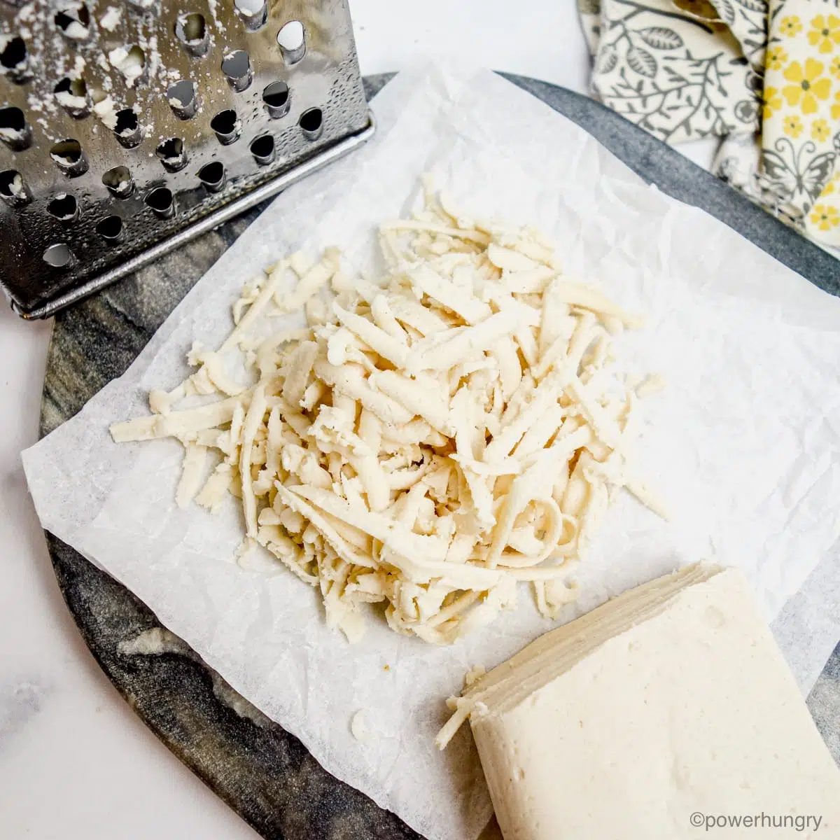grated Oil-Free Vegan Mozzarella that Melts, Grates & Slices, grated on white parchment paper