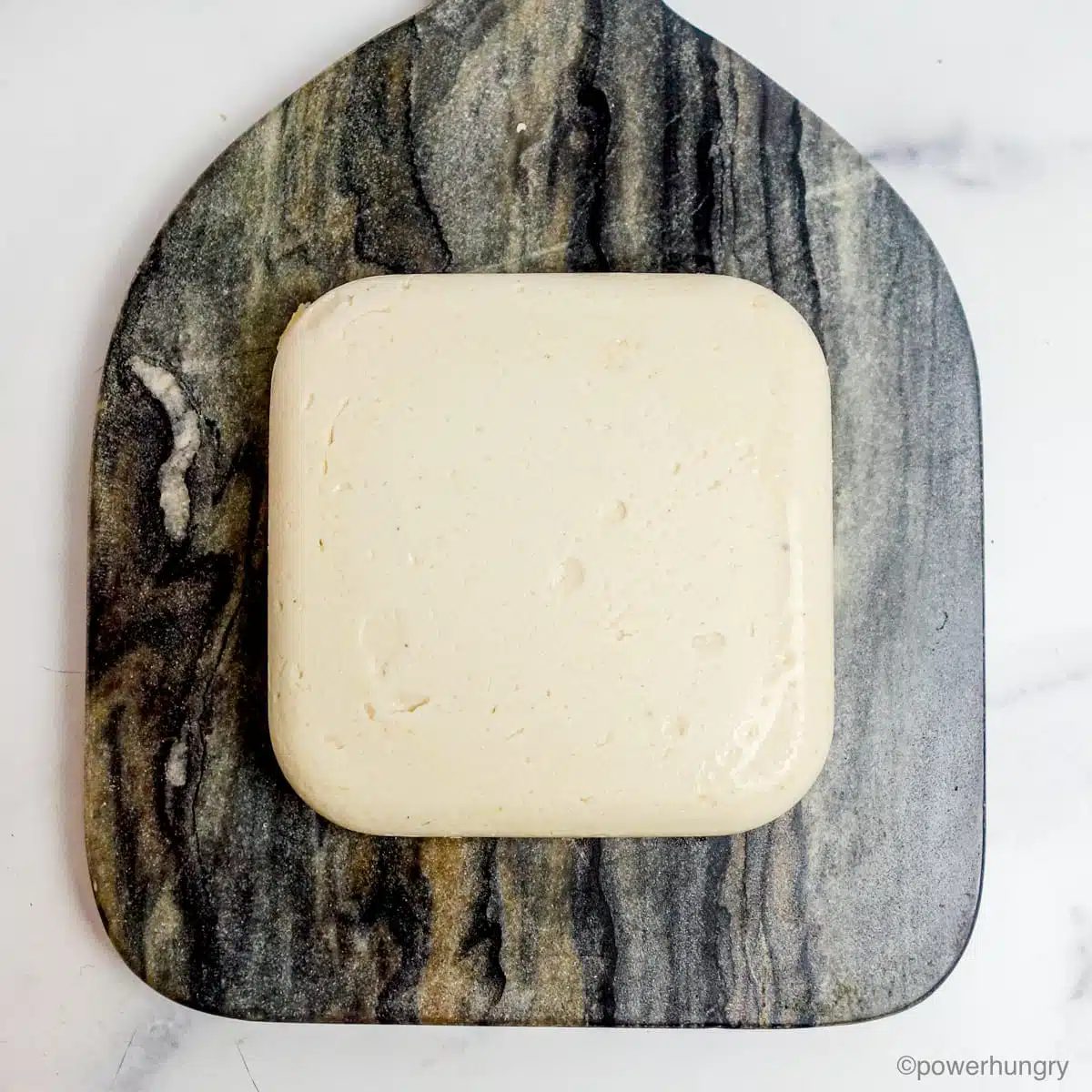 molded Oil-Free Vegan Mozzarella that Melts, Grates & Slices on a grey marble cutting board