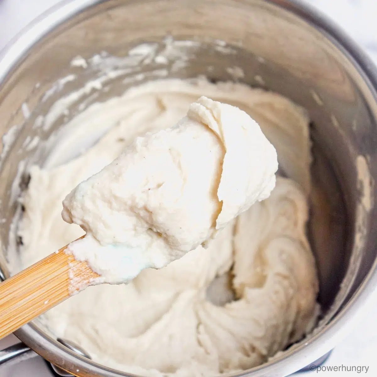 closeup of oil-free slice and grate vegan mozzarella cheese in a saucepan
