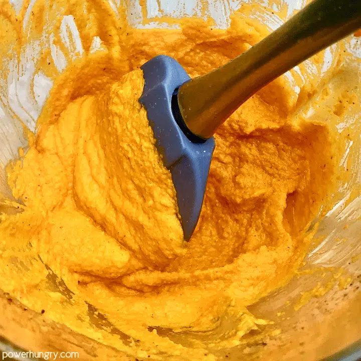 roasted carrot hummus being blended and stirred in a blender