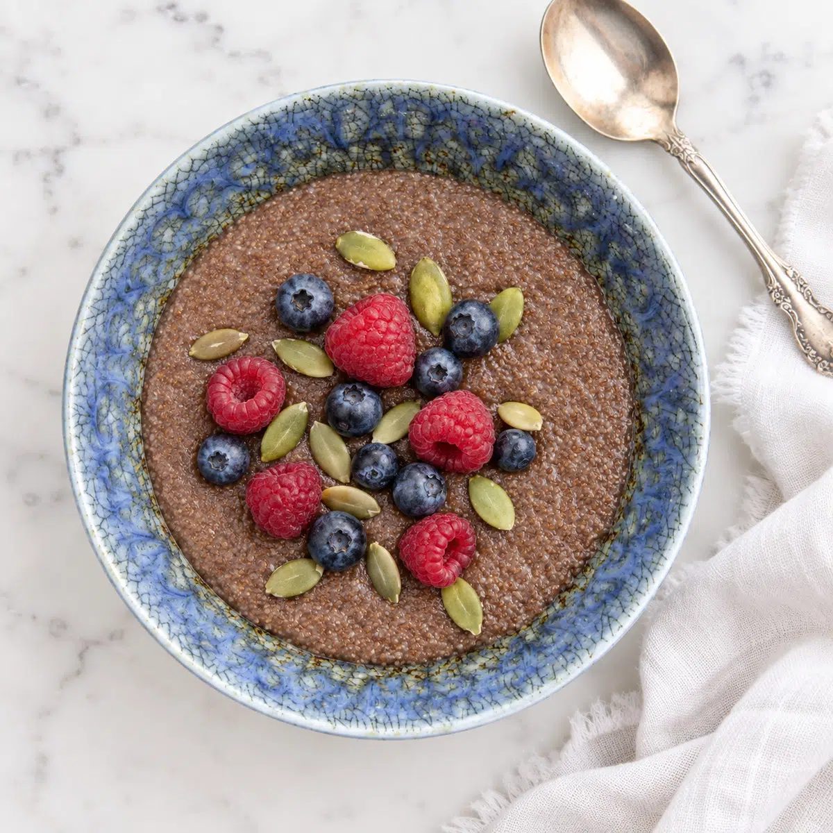 teff porridge in blue bowl topped with pepitas and berries