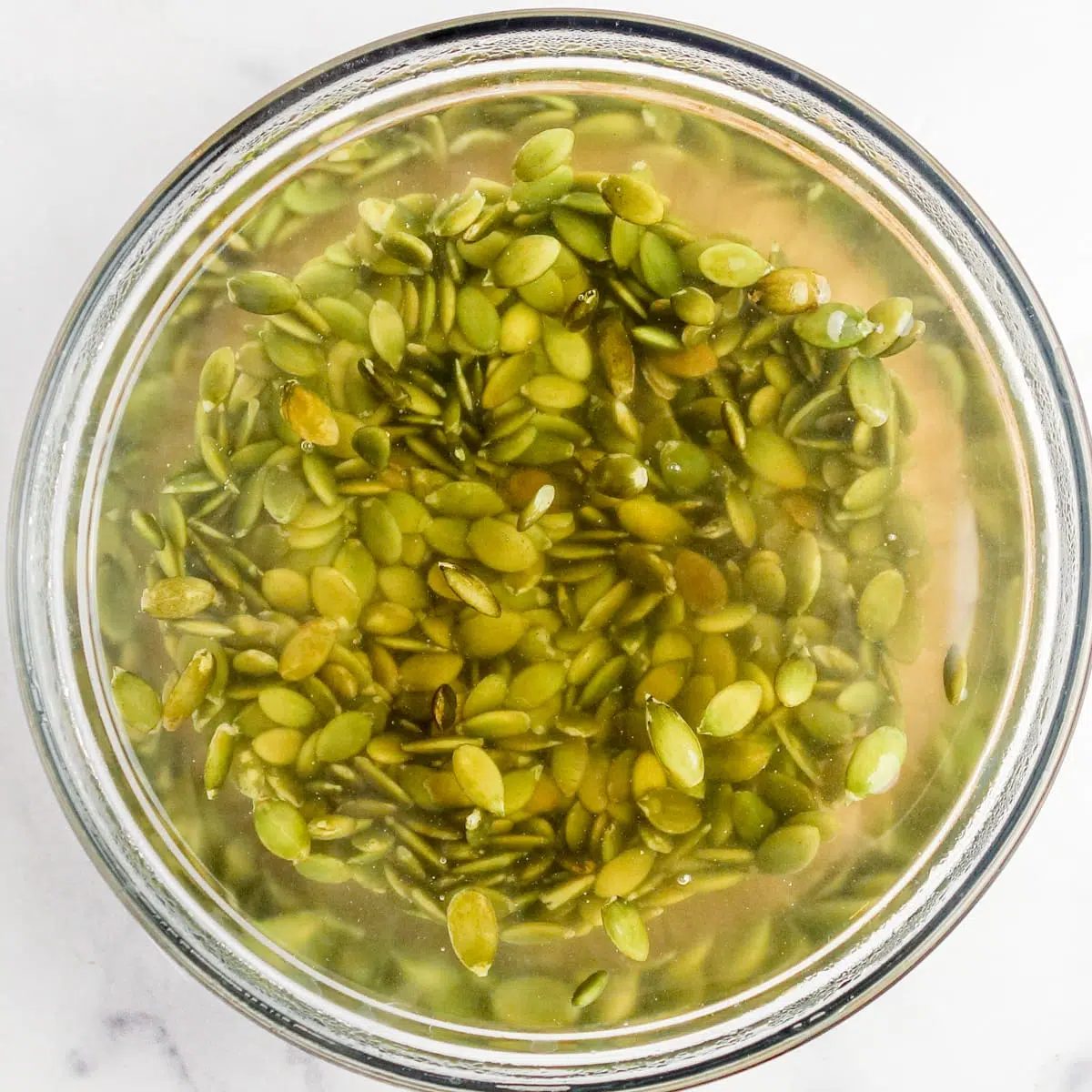 soaked pepitas (green pumpkin seeds) in a glass bowl