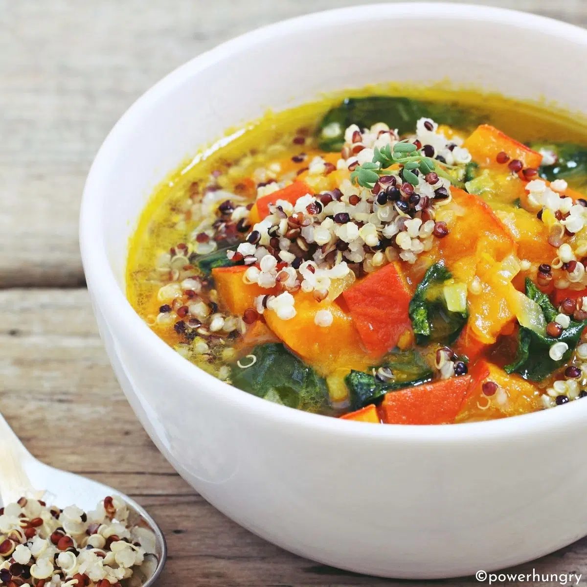 quinoa minestrone in a white bowl on a wood surface