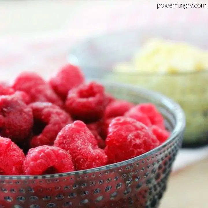 A bowl of fresh raspberries and a bowl of blanched almondflour in the background