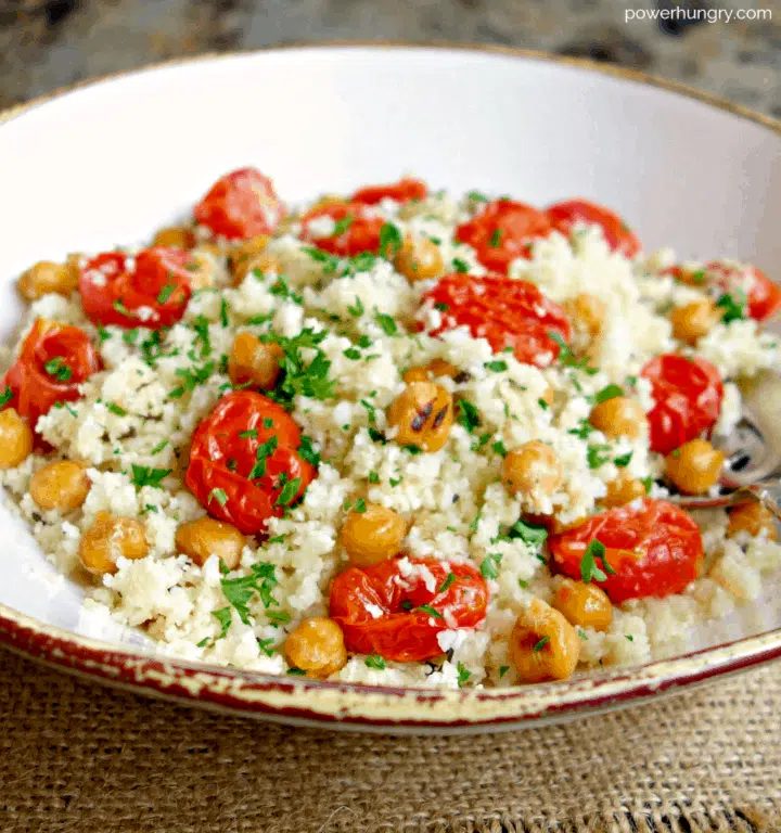 close up of roasted chickpea roasted tomatoes and cauliflower salad in a white bowl