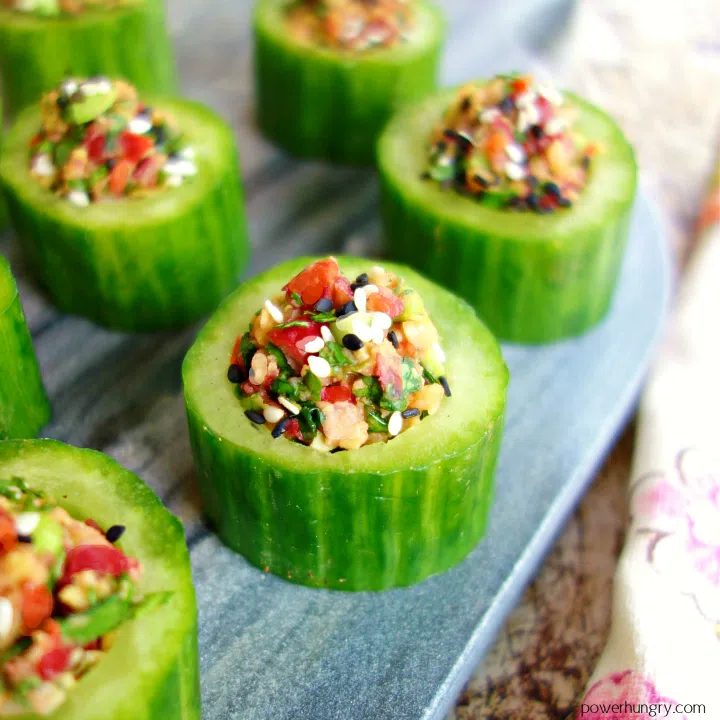Sesame Sriracha Stuffed Cucumber Cups lined up on a marble cutting board