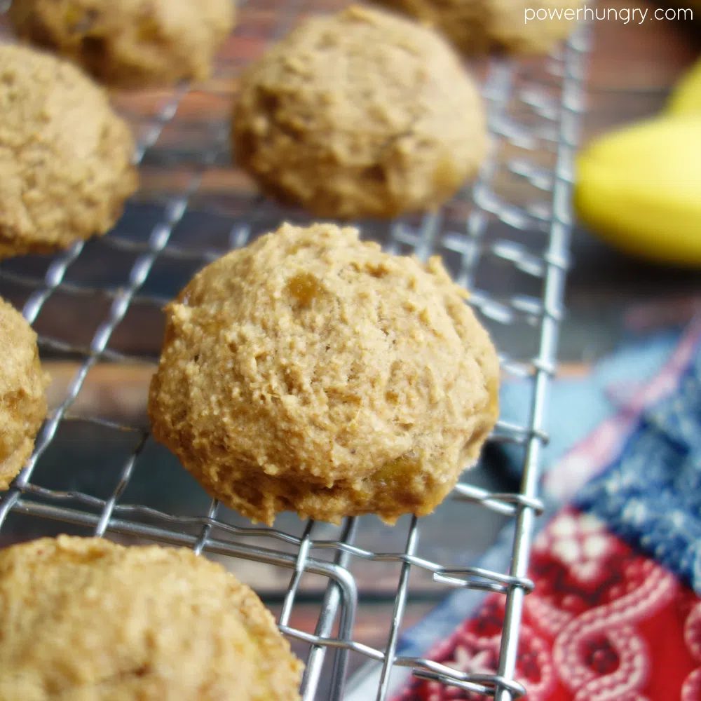 banana oat cookies on a wire cooling rack with a banana and a colorful napkin in the background