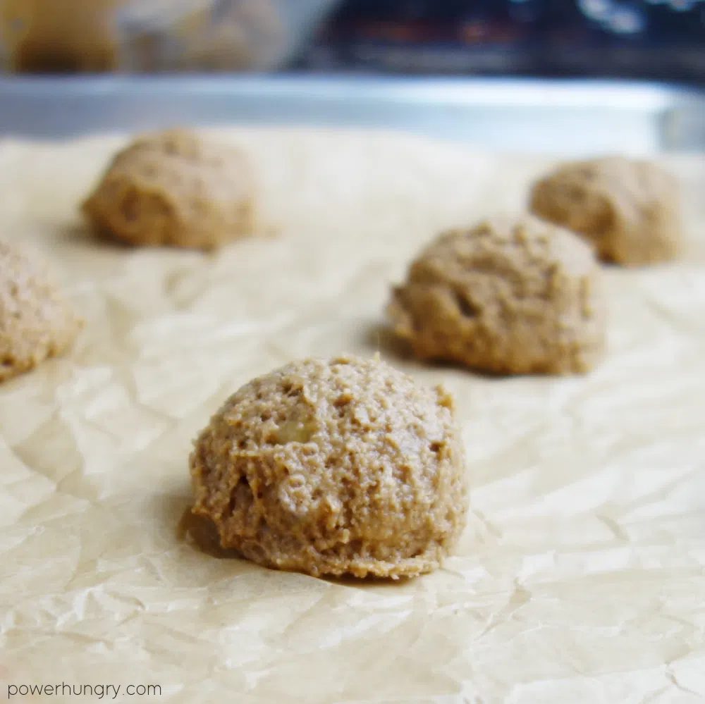 mounds of unbaked cookie dough on a parchment lined baking sheet