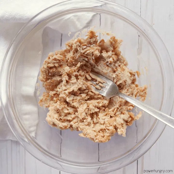 mashed pinto beans in a glass bowl with a silver fork inside