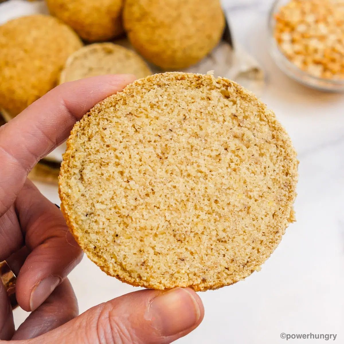 a sliced half of a split pea bread roll held up by a woman's hand