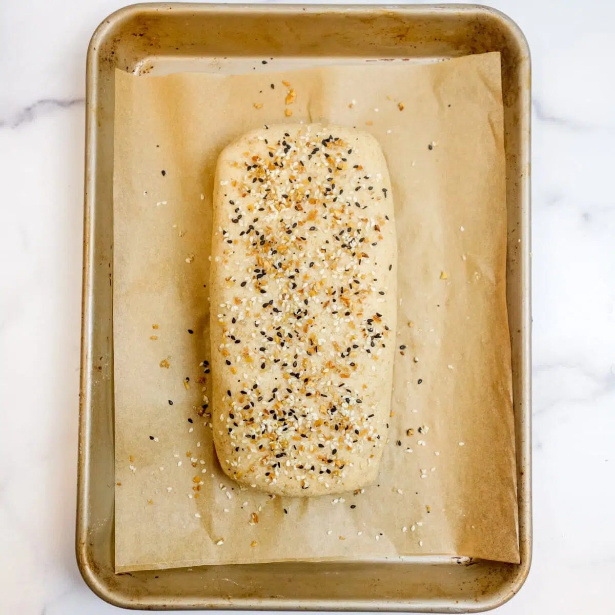 unbaked loaf of split pea bread sprinkled with seeds