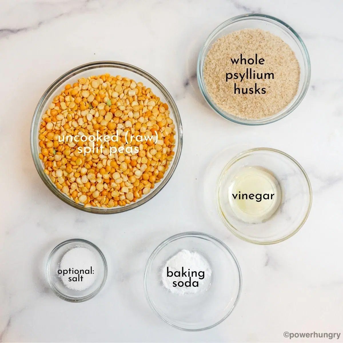 ingredients for small split pea bread displayed in glass bowls on a white marble surface