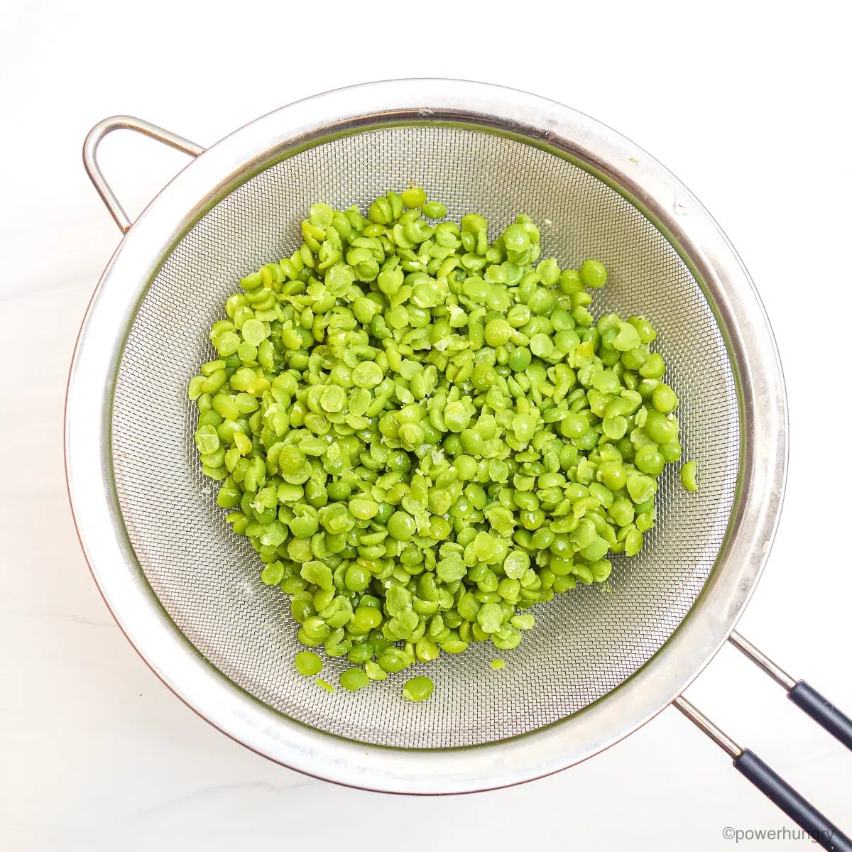 drained split peas in a silver mesh strainer