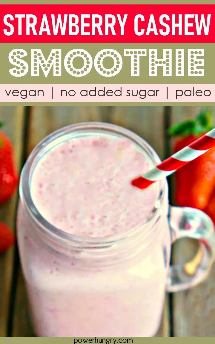 ovehead shot of strawberry cashew smoothie in a glass mug with a red and white straw sticking out