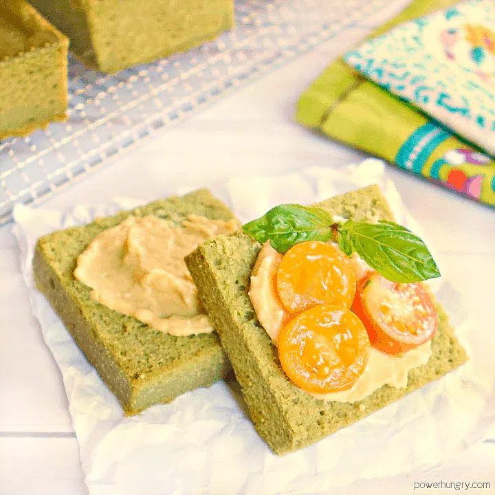 fresh herb lentil bread, cut in half, and topped with hummus and sliced tomatoes