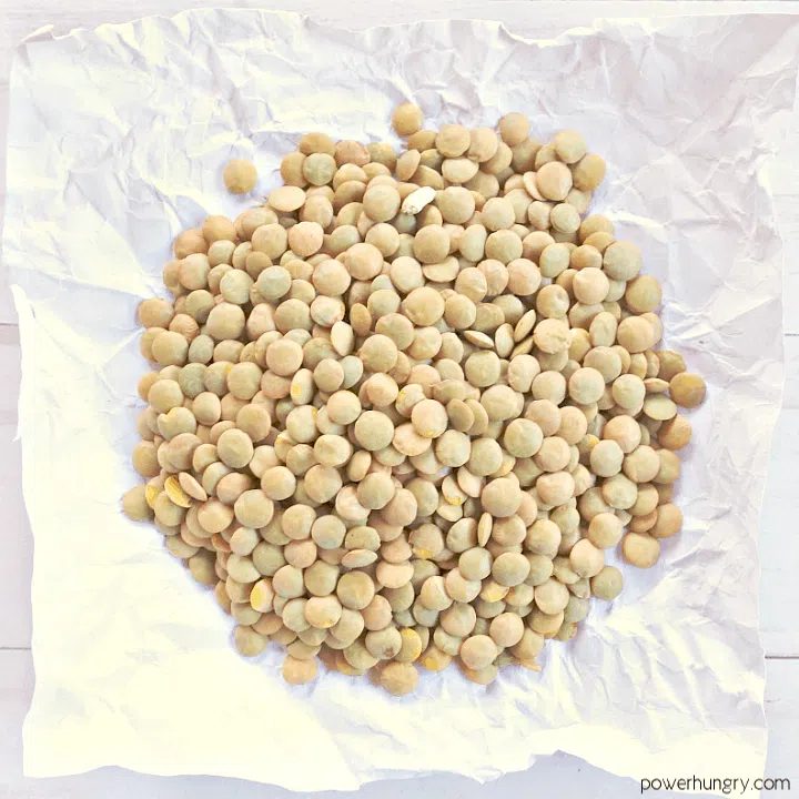 a pile of tan lentils on a piece of white parchment paper