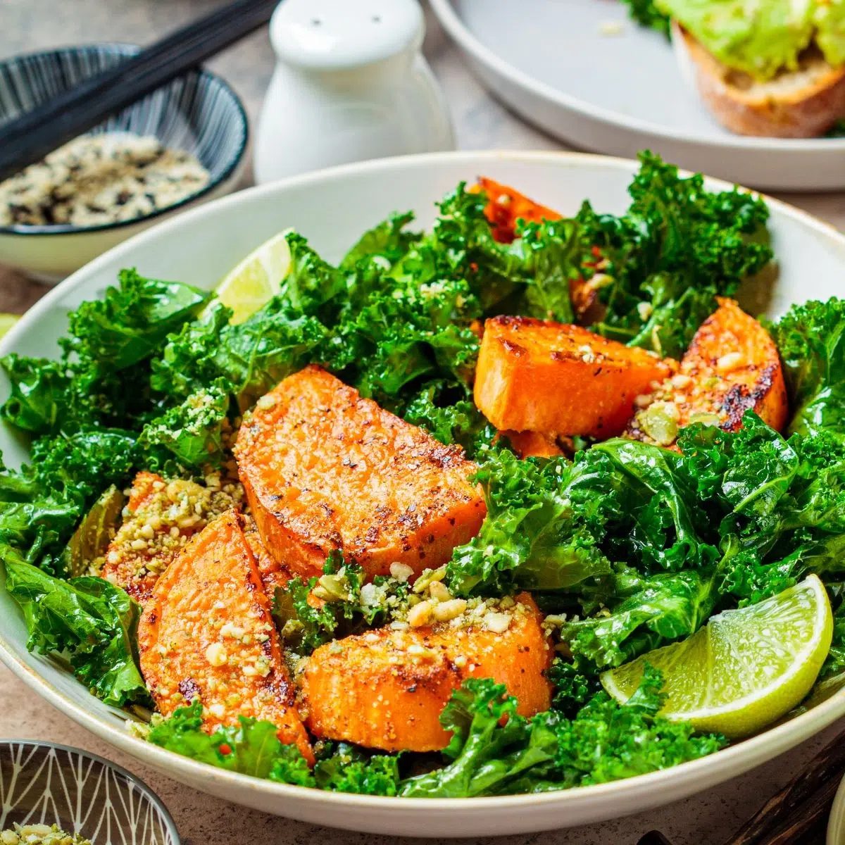 sweet potato and kale salad in a bowl with a lime wedge