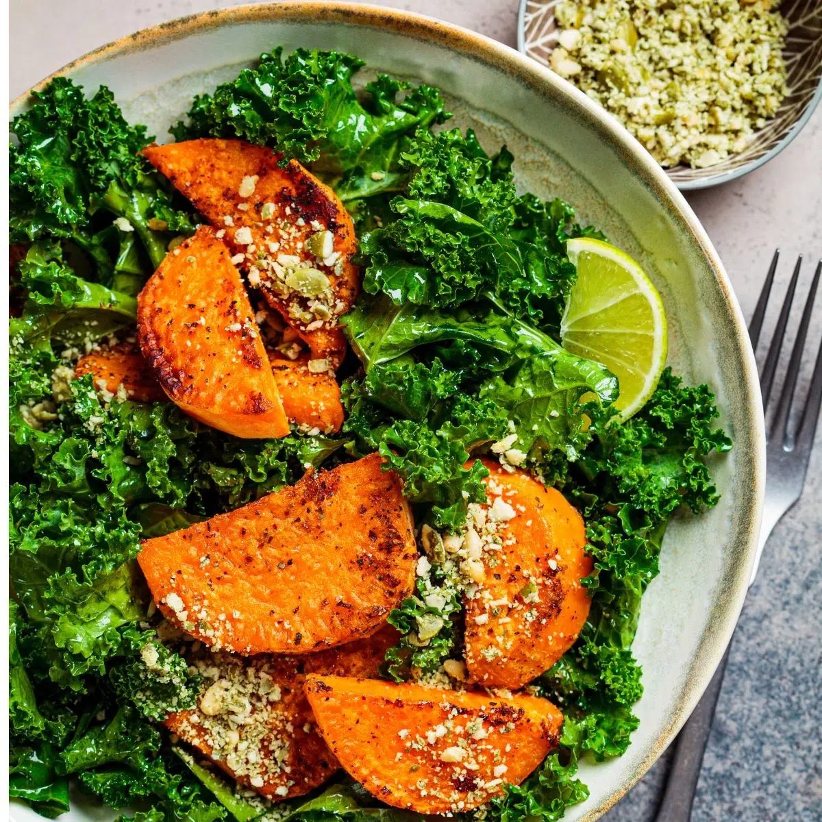 kale salad in a white bowl with pumpkin seeds