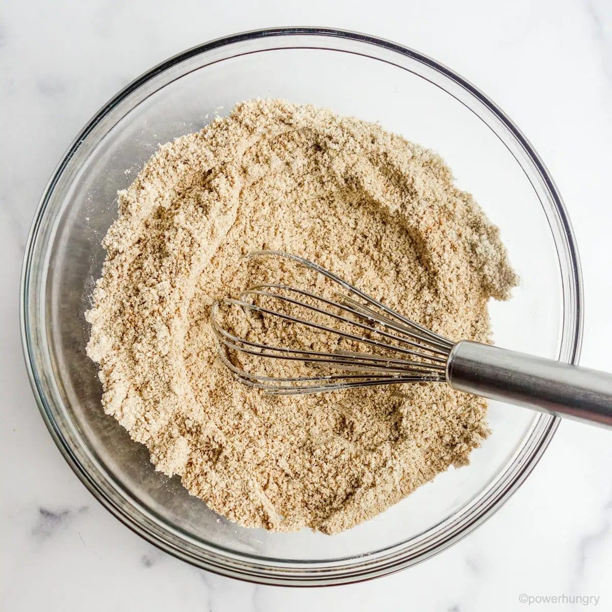 a medium glass bowl with a whisk, filled with the dry ingredients for vegan tiger nut flour cookies