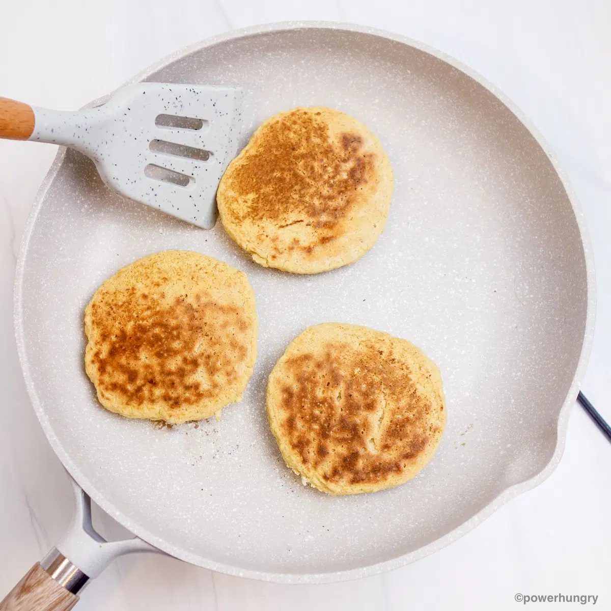 millet pancakes in a nonstick white skillet