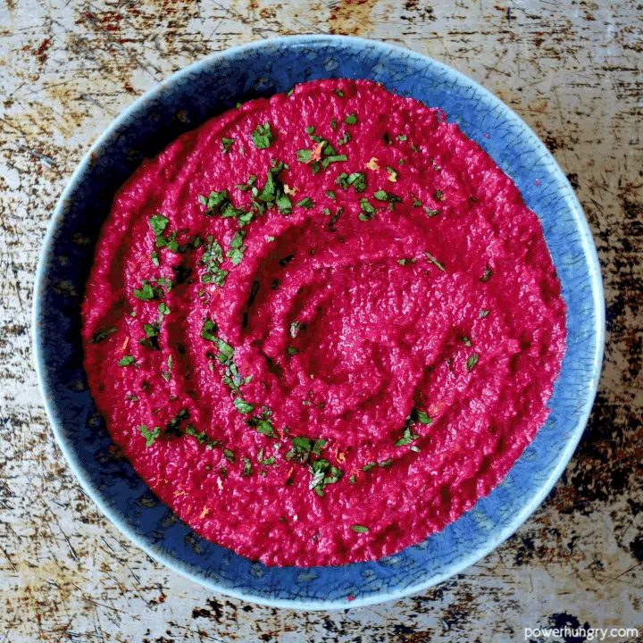 overhead shot of beet and toasted pepita dip in a blue pottery bowl