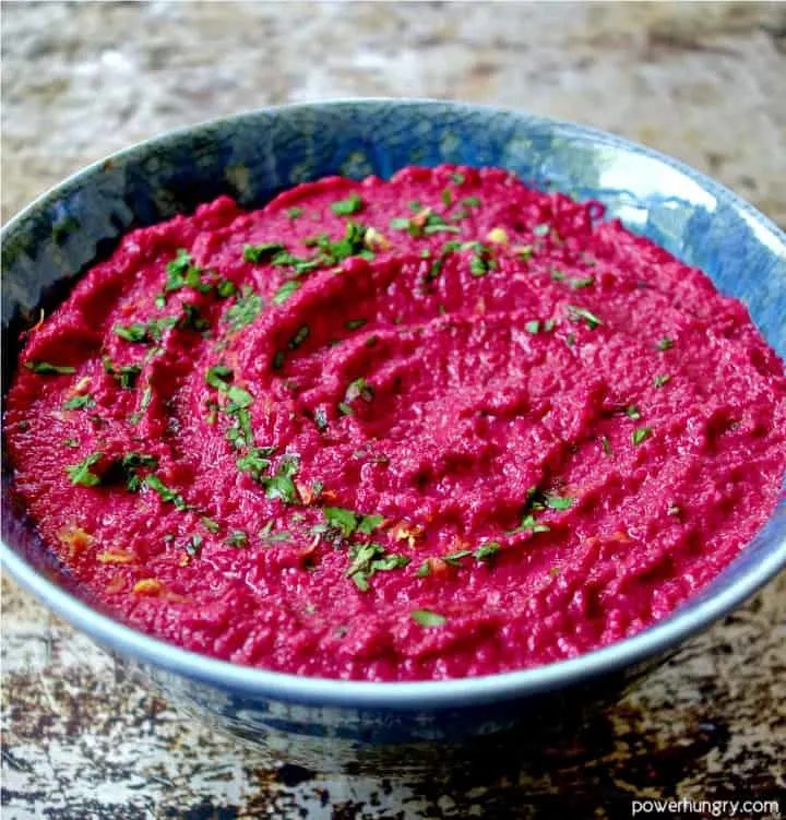beet and toasted pepita dip in a blue pottery dish, sprinkled with herbs and lemon zest