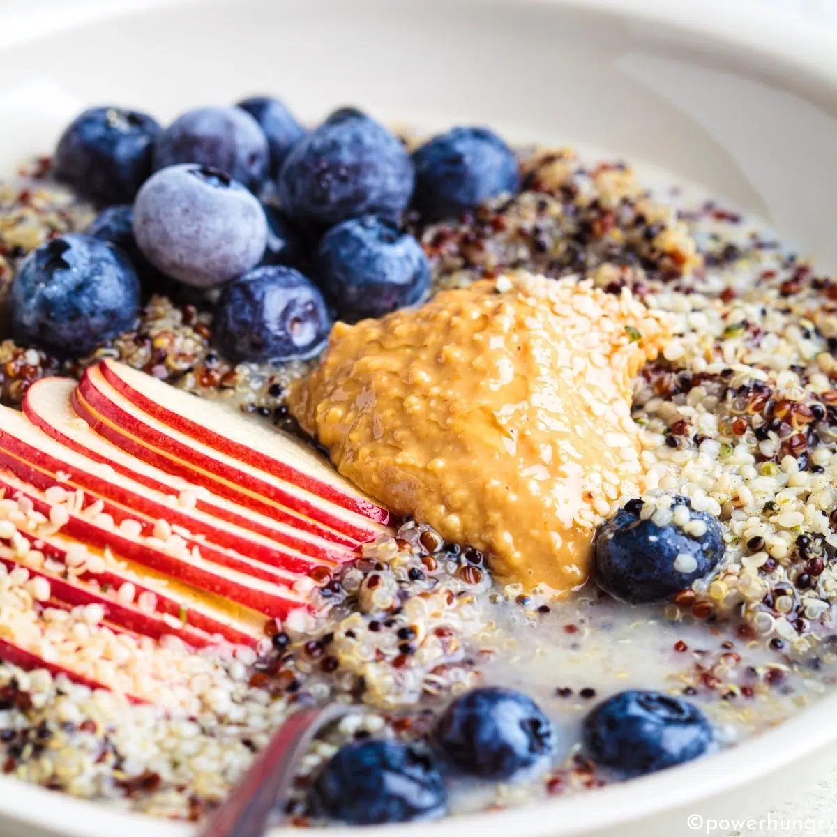 quinoa porridge breakfast bowl, topped with nut butter and fruits