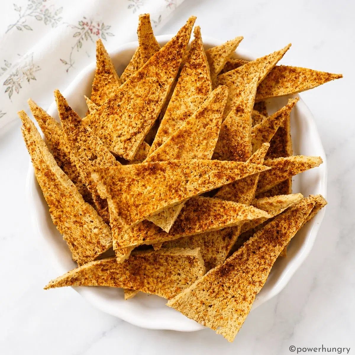 overhead shot of a white bowl filled with crispy tofu chips