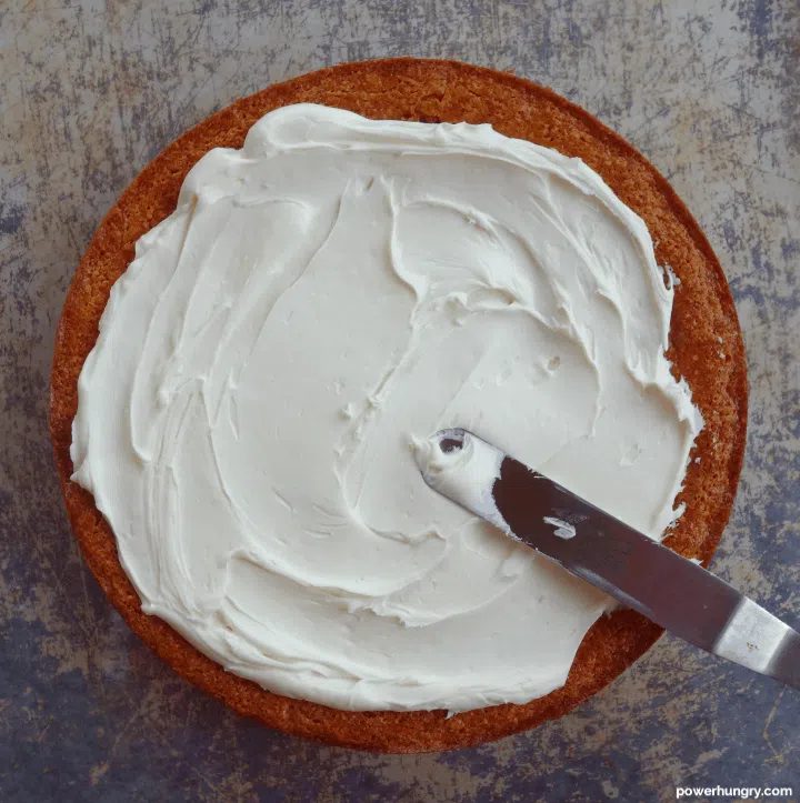 overhead shot of cake being frosted with vegan vanilla frosting