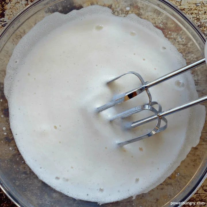 a glass bowl with whipped aquafaba (chickpea liquid)