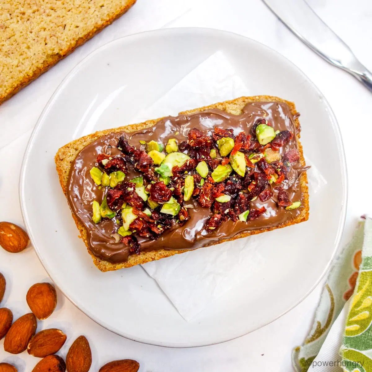 a slice of almond bread topped with vegan Nutella and pistachios