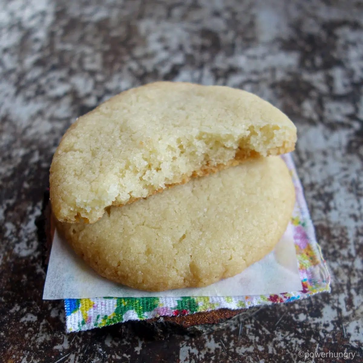 two vegan almond flour sugar cookies stacked on a colorful napkin