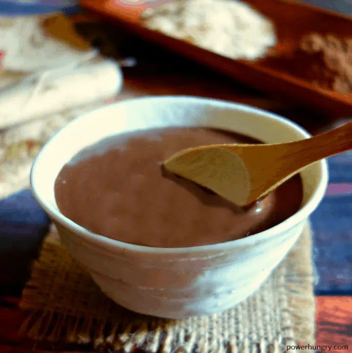 brownie batter breakfast oats in a white bowl with a wooden spoon inserted