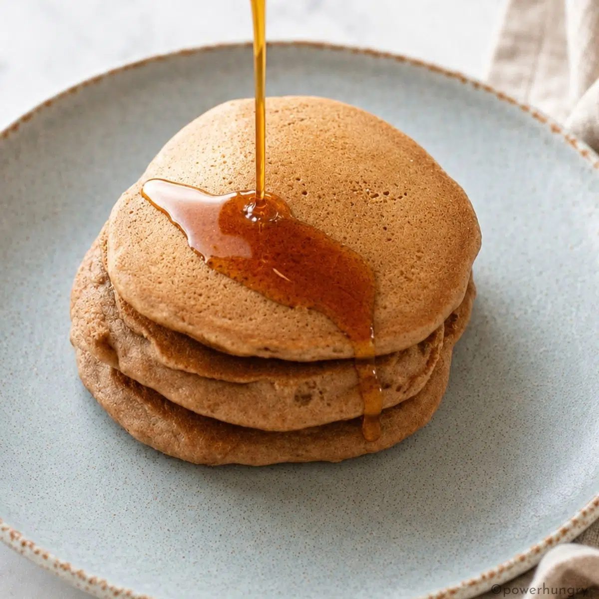 stack of vegan buckwheat pancakes with a drizzle of maple syrup