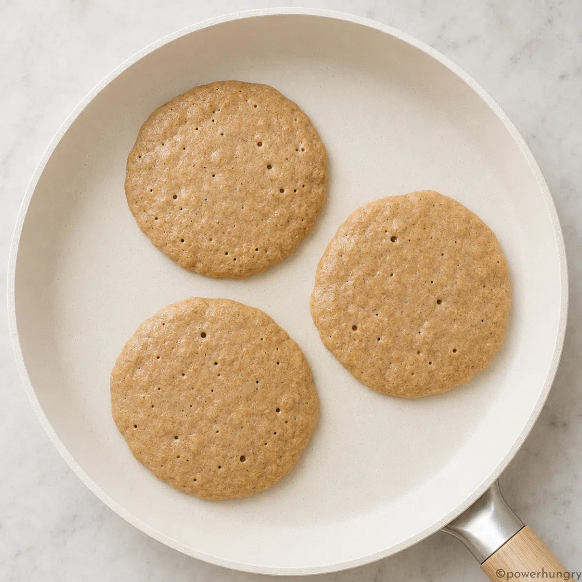 nonstick ceramic skillet with three buckwheat pancakes that are cooking